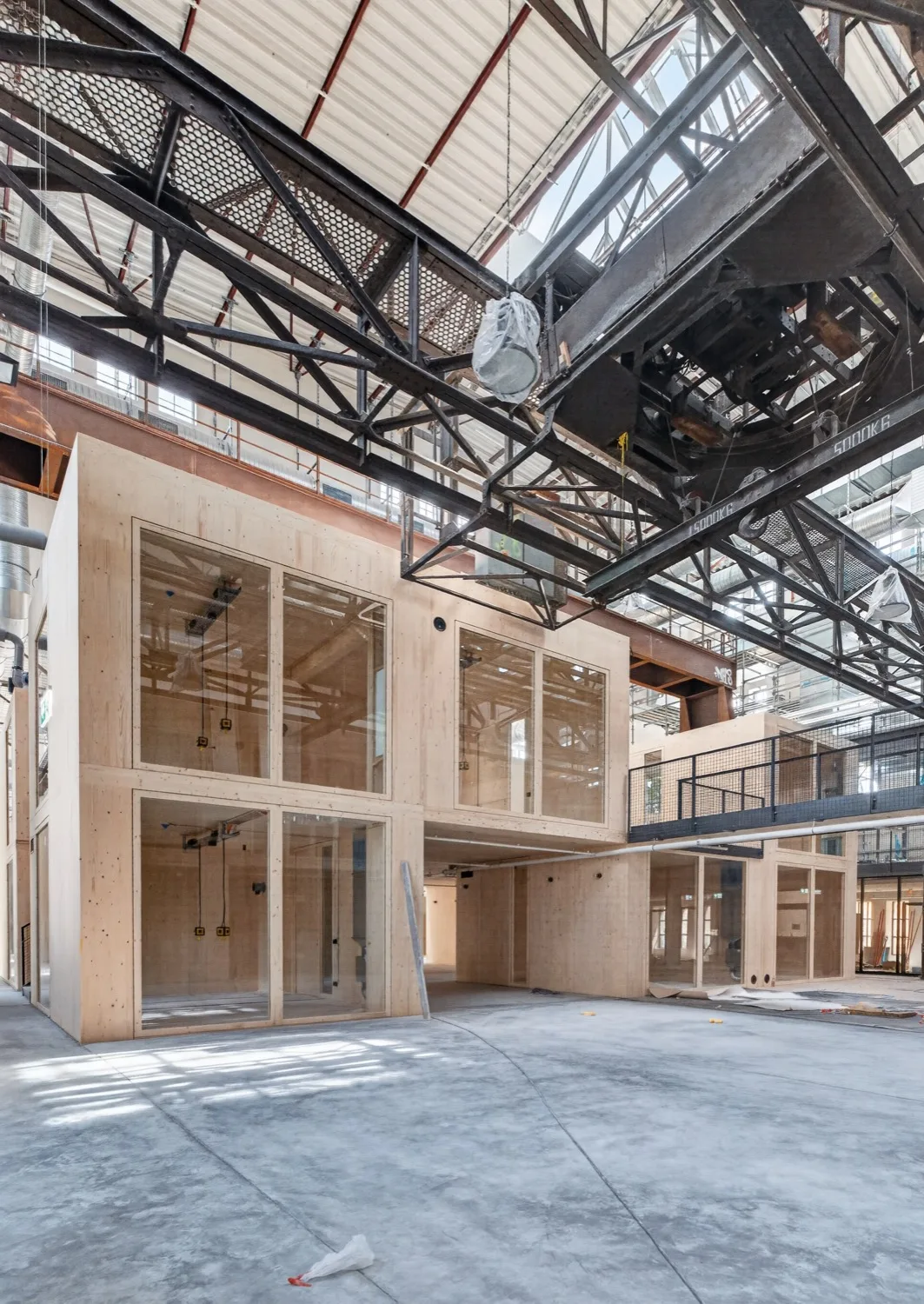 Brettsperrholz-Baukörper unter dem historischen Stahlfachwerk der Jutierhalle